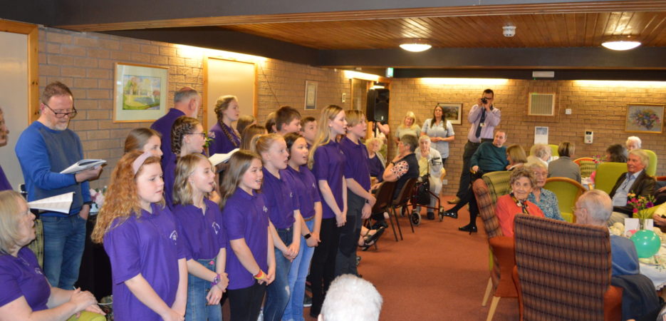 Young operatic choir singing to residents